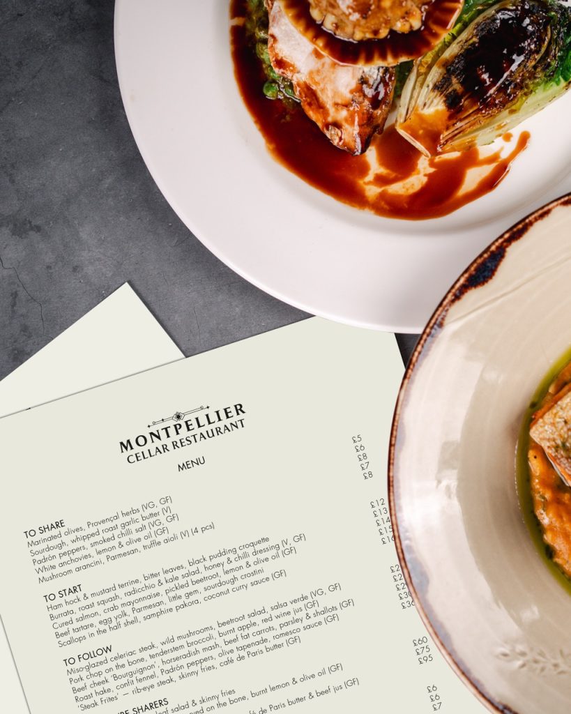 Montpellier cellar restaurant menus next to two plates of food.