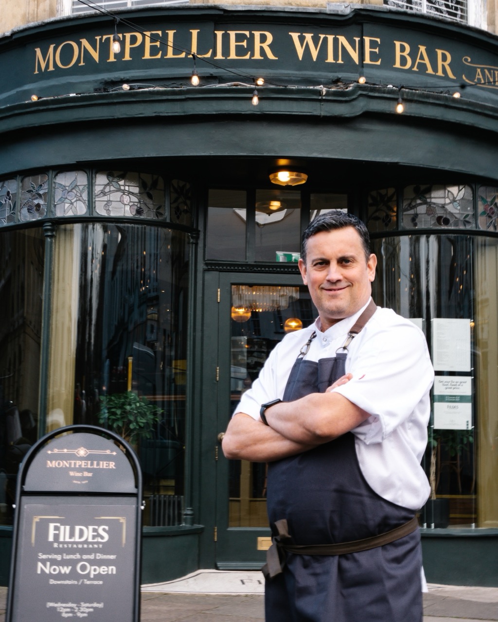 http://Chef%20Tom%20Rains%20in%20stood%20in%20front%20of%20the%20Montpellier%20Wine%20Bar%20with%20his%20arms%20folded.