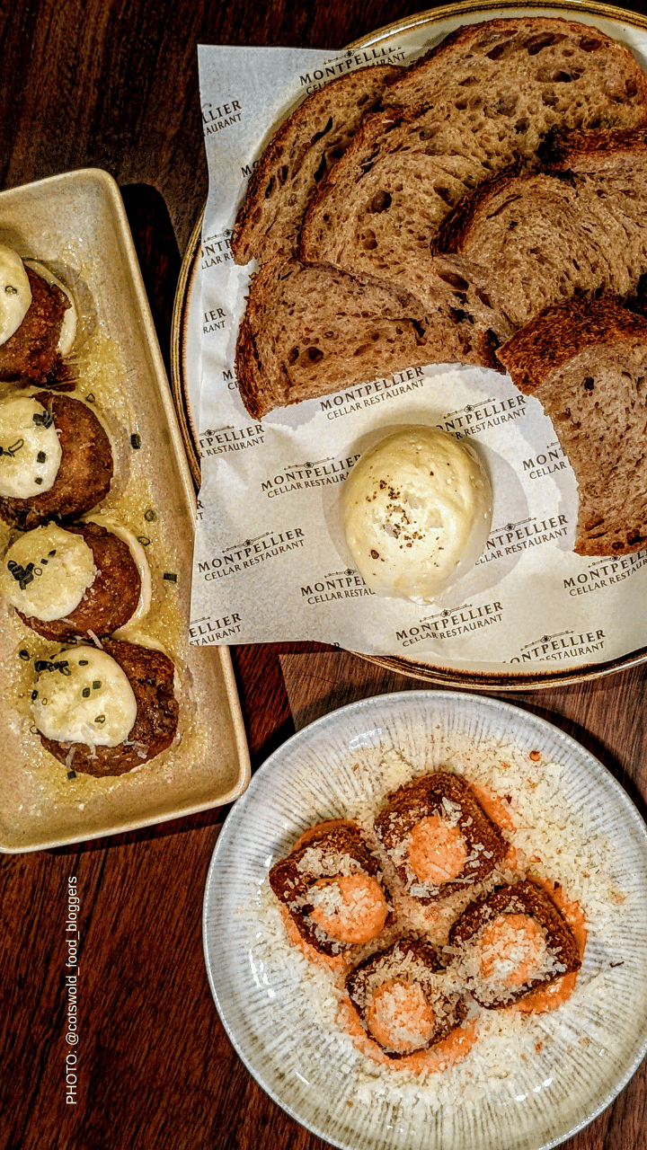 Round artisanal loaf of bread on parchment with a knob of butter, set on a dark wood table.
