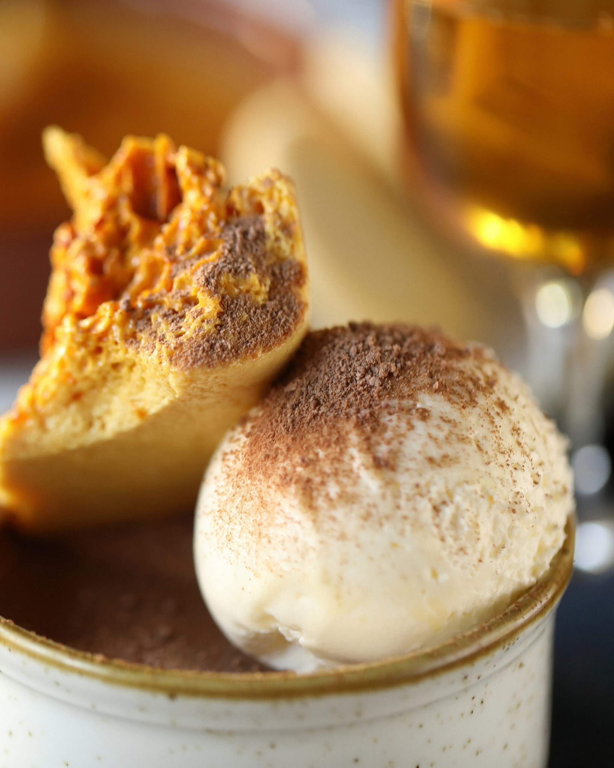 http://Close-up%20of%20vanilla%20ice%20cream%20scoops%20with%20cinnamon%20dusting%20and%20a%20crumbly%20cookie,%20against%20a%20warm%20blurred%20background.