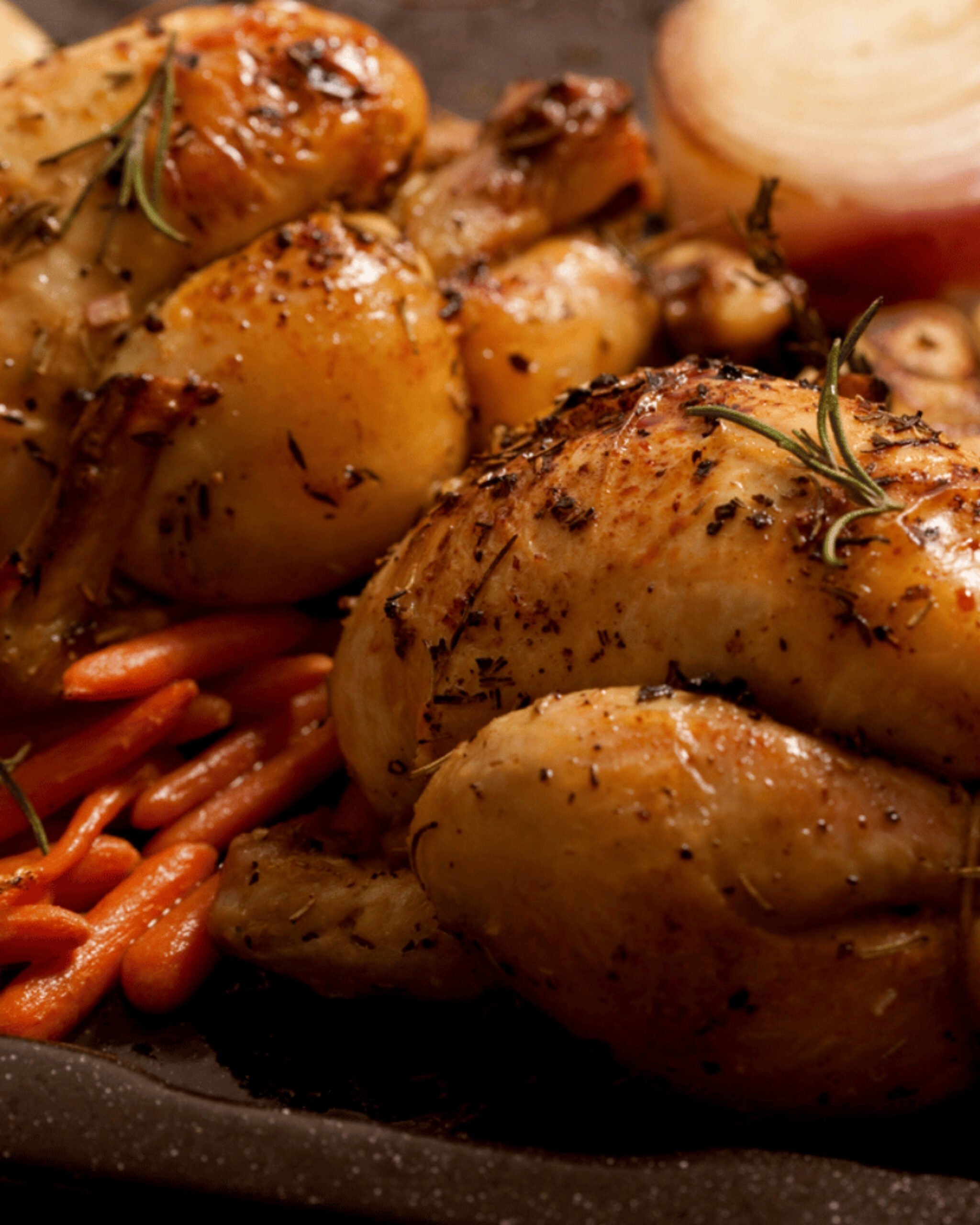 http://Close-up%20of%20crispy%20roasted%20potatoes%20seasoned%20with%20herbs%20and%20pepper,%20with%20sprigs%20of%20rosemary%20and%20a%20side%20of%20carrot%20ribbons%20visible.